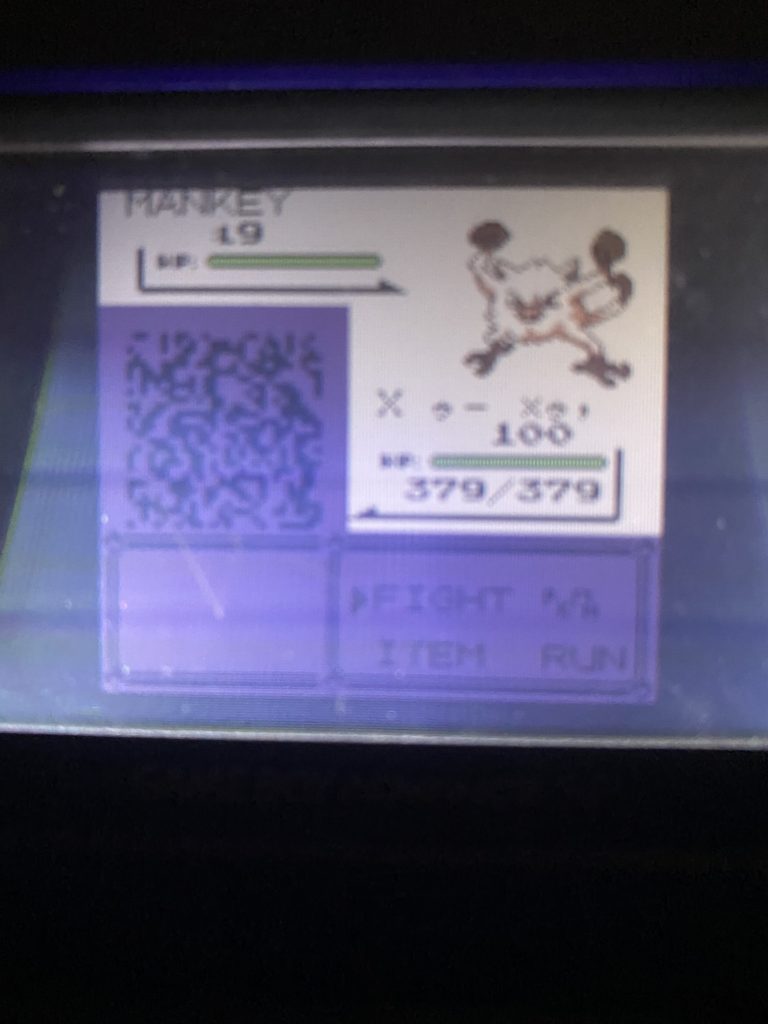 A photo of a Game Boy SP screen, showing a Mankey fighting a block of junk pixels with a random data name. The bottom of the screen, as well as the block of pixels, is inexplicably colored purple.